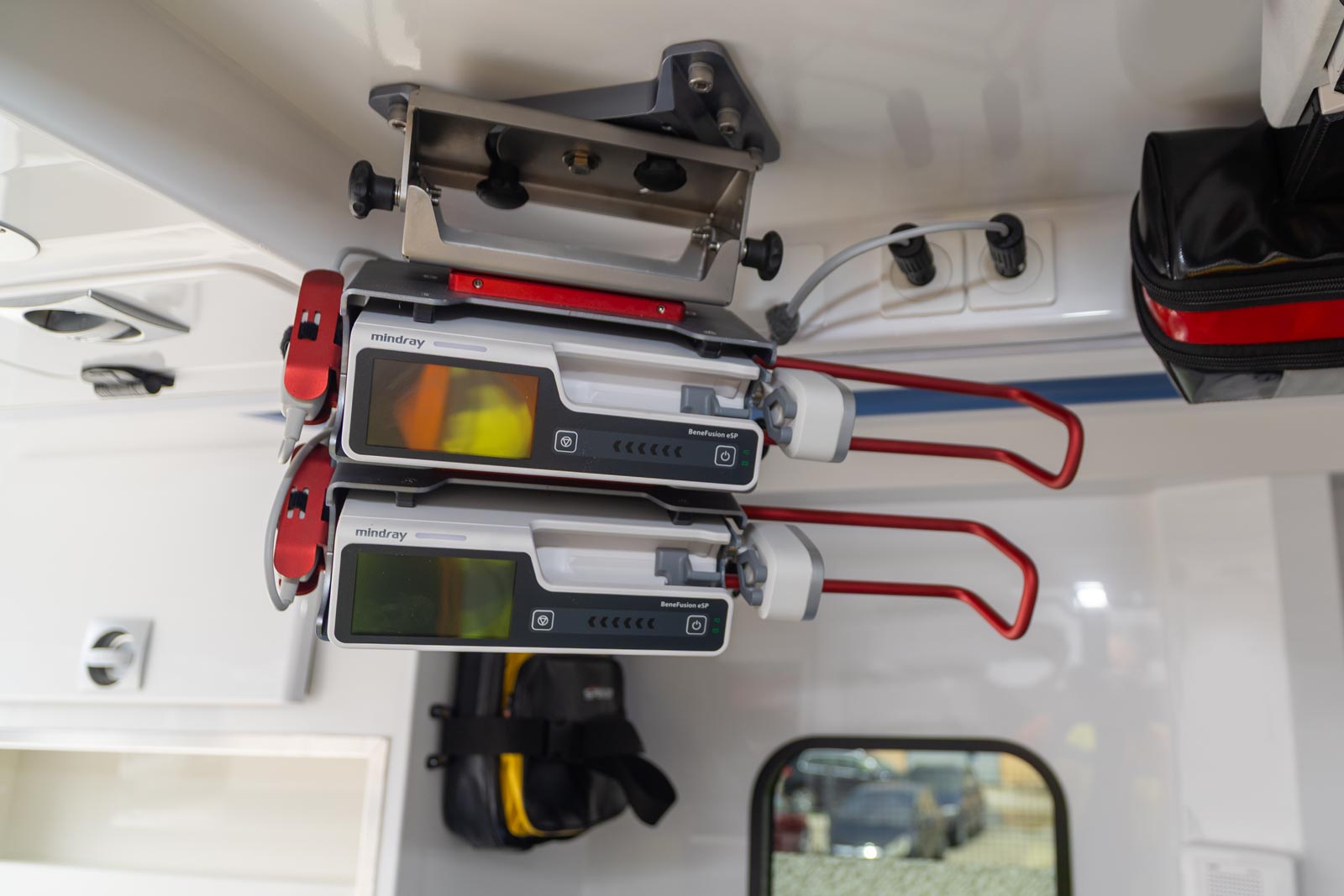 Close-up of two smart infusion syringe pumps stacked on a ceiling mount inside a modern emergency ambulance.